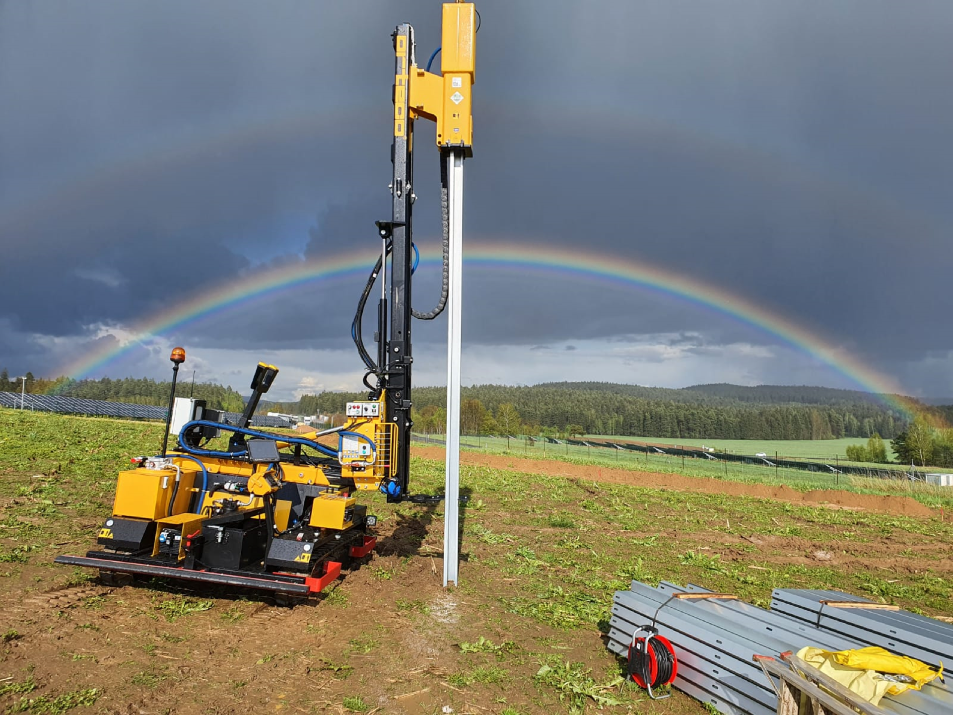 Orteco-Rammmaschine mit Regenbogen auf einer Solarbaustelle